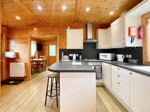 a kitchen with white cabinets and a black counter top at Magnolia Lodge-Uk46280 in Camerton