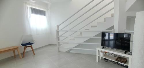 a living room with a tv and a staircase at Residência Alto Saco, Double room with private bathroom in Tarrafal