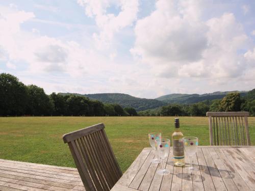 a bottle of wine sitting on a wooden table with glasses at Cider Mill Lodge - Hw7420 in Tintern