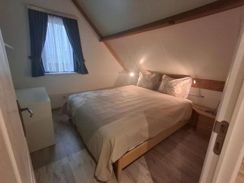 a bedroom with a large bed with a window at De zeebries in De Haan