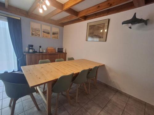 a dining room with a wooden table and chairs at De zeebries in De Haan
