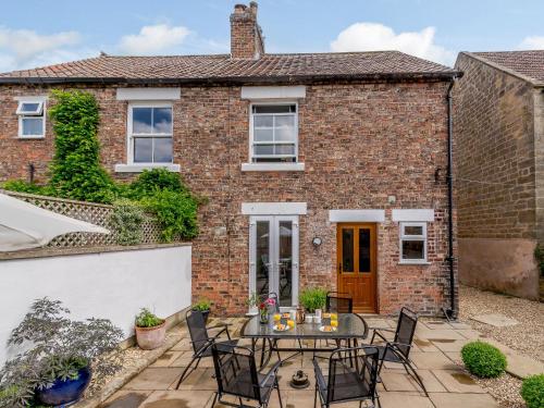 a patio in front of a brick house with a table and chairs at The Old Post Office in Baldersby