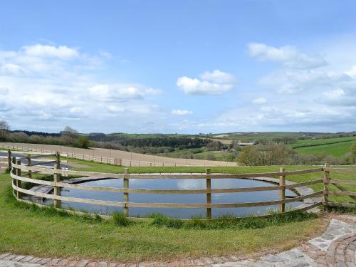 a wooden fence and a pond in a field at Bridge House - Ukc1340 in North Molton
