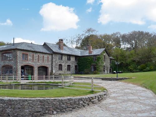 a large stone house with a pond in front of it at Bridge House - Ukc1340 in North Molton