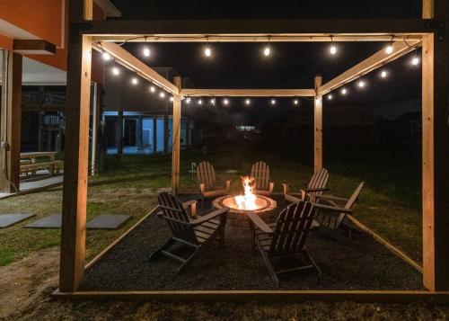 StingareeにあるSea Glass Retreat homeのパティオ(テーブル、照明付きのパーゴラの下の椅子付)