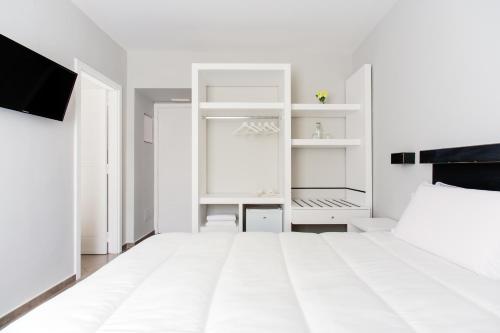 a white bedroom with a bed and white shelves at Palazzo Gargiulo Luxury Rooms & Suites in Sorrento