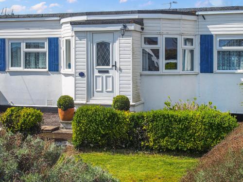 a white house with a blue door and some bushes at Seagull Cottage in Pagham
