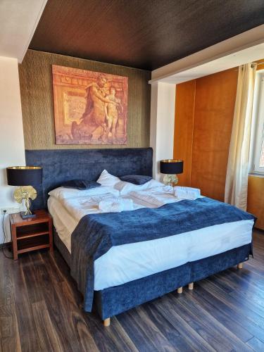 a bedroom with a large bed with a painting on the wall at In Spirit, hotel v Rožnovském pivovaru - Pivní Lázně, Wellness & Čokoládovna in Rožnov pod Radhoštěm