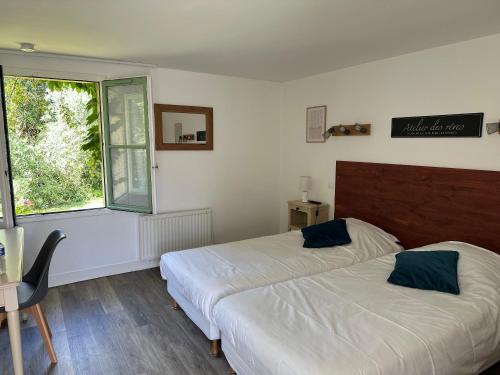 a bedroom with two beds and a window at Logis Hôtel La Demeure du Perron in Quettehou