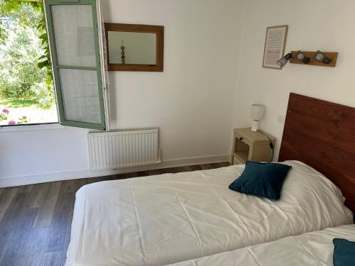 a bedroom with a bed with a blue pillow on it at Logis Hôtel La Demeure du Perron in Quettehou