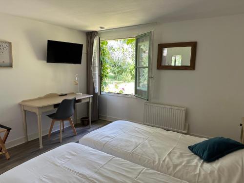 a bedroom with a bed and a desk and a window at Logis Hôtel La Demeure du Perron in Quettehou