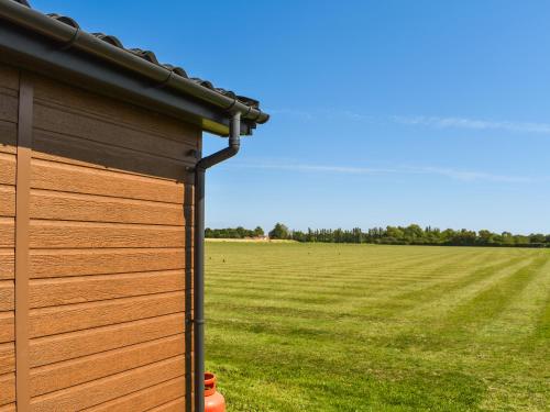 a wooden building with a field in the background at Lodge 38 in Stonham Aspall