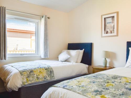 two beds in a room with a window at Lodge 38 in Stonham Aspall