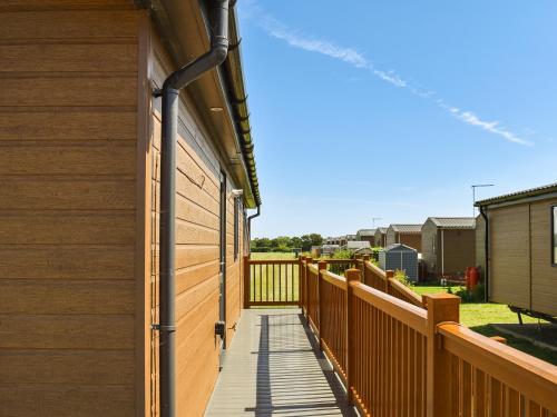 a wooden walkway next to a building with a fence at Lodge 38 in Stonham Aspall