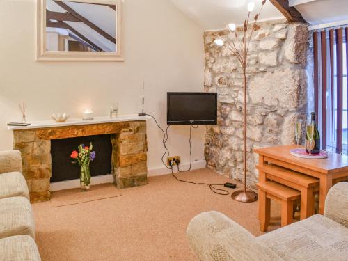 a living room with a stone fireplace and a tv at The Piggery - Uk49014 in Liskeard