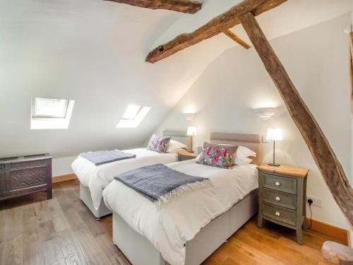 two beds in a attic bedroom with wooden floors at The Coach House - Uk45027 in Gilwern
