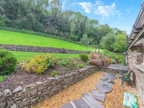a garden with a stone wall and a bench at The Coach House - Uk45027 in Gilwern
