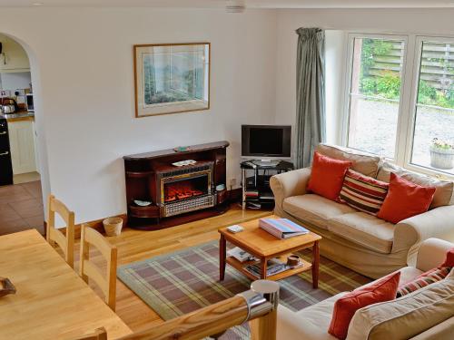 a living room with a couch and a fireplace at Rathlin Coach House in Comrie
