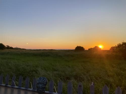 a sunset over a field with a fence at The View in Whitstable