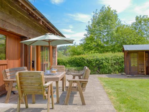 a wooden table and chairs with an umbrella at Applebarrel Barn in Dunkeswell