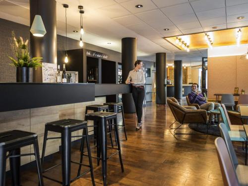 a woman standing at a bar in a restaurant at Mercure Hotel Berlin Zentrum Superior in Berlin