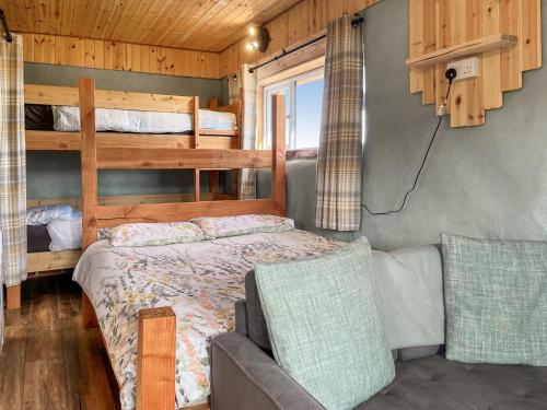 a bedroom with a bunk bed and a couch at Honeysuckle Bale Cabin - Uk49073 in Ballindalloch