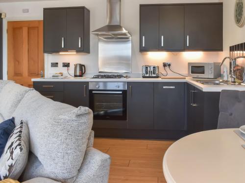 a kitchen with black cabinets and a gray couch at Waterside Retreat in Carnforth