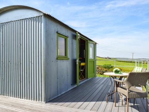 a blue shed with a table and chairs on a deck at Martha's Place in Bradley