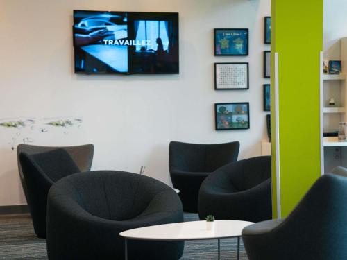 a waiting room with chairs and a table and a tv at ibis Styles Caen centre gare in Caen