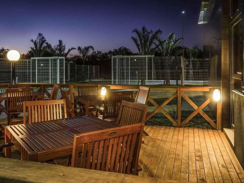 a wooden deck with tables and chairs at night at Ibis Porto Alegre Assis Brasil in Porto Alegre