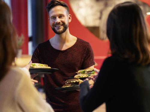 a man is holding two plates of food at Ibis Porto Alegre Assis Brasil in Porto Alegre