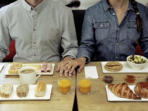two people sitting at a table with food and drinks at Ibis Porto Alegre Assis Brasil in Porto Alegre