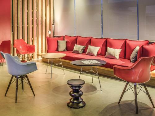 a red couch in a room with chairs and tables at Ibis Porto Alegre Assis Brasil in Porto Alegre