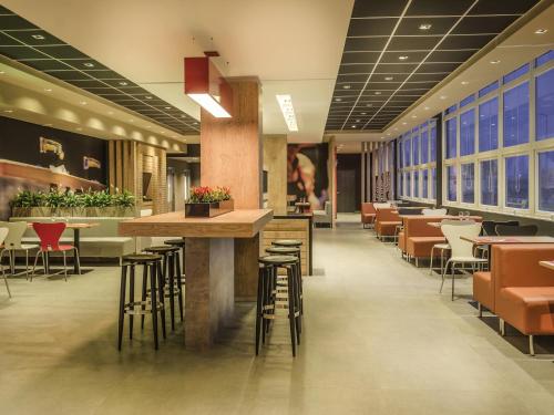 a restaurant with chairs and a bar with stools at Ibis Porto Alegre Assis Brasil in Porto Alegre