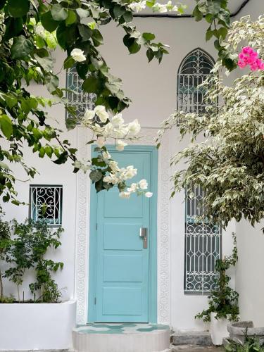 a blue door on a white house with flowers at Studio Turquesa Kasbah Tangier in Tangier