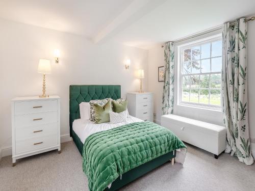 a bedroom with a green bed and a window at The Farmhouse - Uk45171 in Southwell