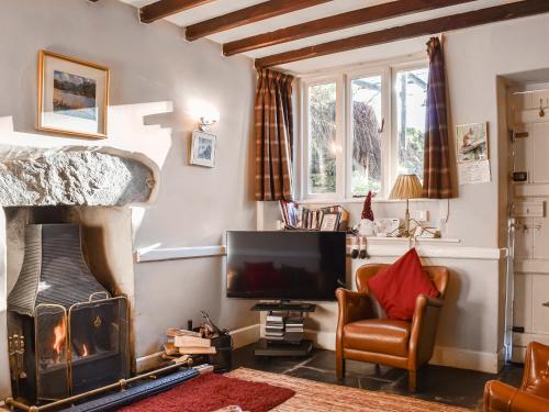 a living room with a fireplace and a television at Tarn Cottage in Grasmere