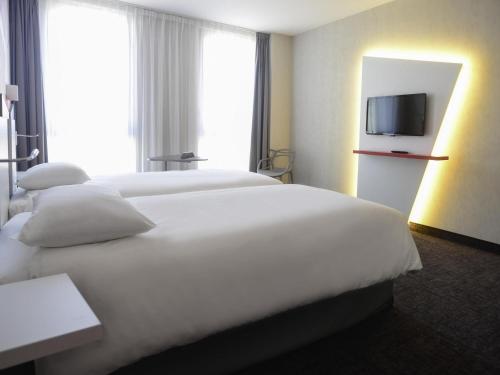 a hotel room with two beds and a flat screen tv at ibis Styles Poitiers Centre in Poitiers