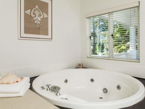 a white bath tub in a bathroom with a window at The Reef House Adults Retreat - Enjoy 28 Complimentary Inclusions in Palm Cove