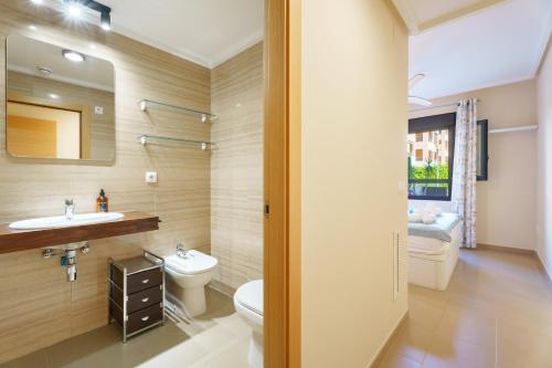 a bathroom with a toilet and a sink and a mirror at Hogar Brisa de las Marinas acogedor apartamento con amplia terraza y acceso directo a las piscinas-Comfortable apartment with spacious terrace and direct pool access in Denia