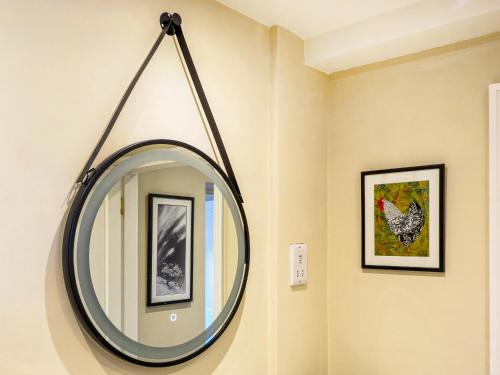 a round mirror hanging on a wall with two pictures at Hollyhock in Tavistock