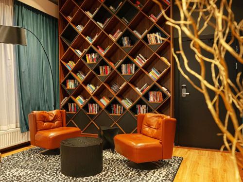 a library with two orange chairs and a book shelf at ibis Styles Wałbrzych in Wałbrzych