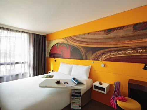 a bedroom with a white bed with a painting on the wall at ibis Styles Montpellier Centre Comedie in Montpellier