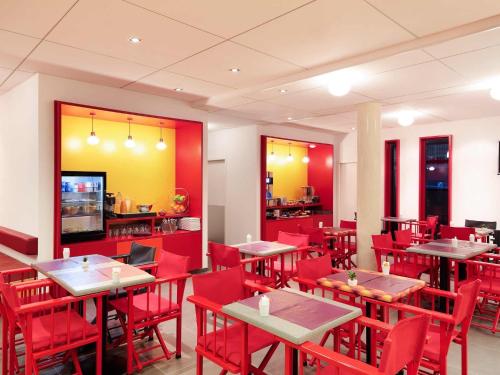 a restaurant with red tables and red chairs at ibis Styles Montpellier Centre Comedie in Montpellier