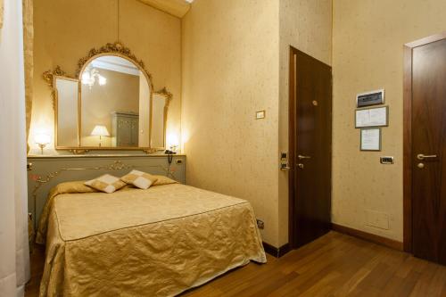 a bedroom with a bed with a mirror and a door at Hotel Al Ponte Mocenigo in Venice