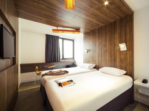 a hotel room with two beds and a television at ibis Styles Niort Poitou Charentes in Vouillé