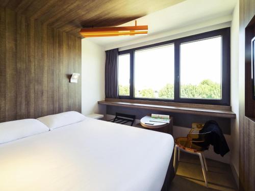 a bedroom with a bed and a window at ibis Styles Niort Poitou Charentes in Vouillé