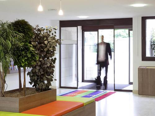 a man walking out of a lobby with a door at ibis Styles Niort Poitou Charentes in Vouillé