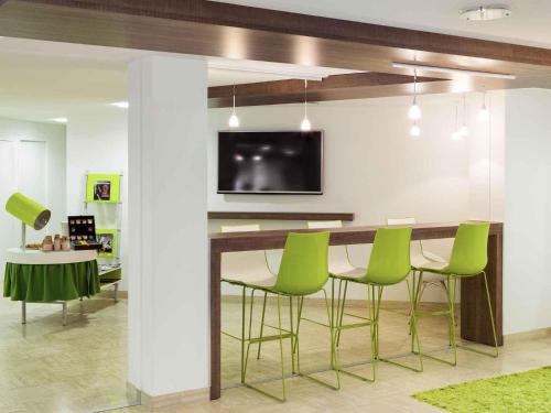 a dining room with a table and green chairs at ibis Styles Niort Poitou Charentes in Vouillé