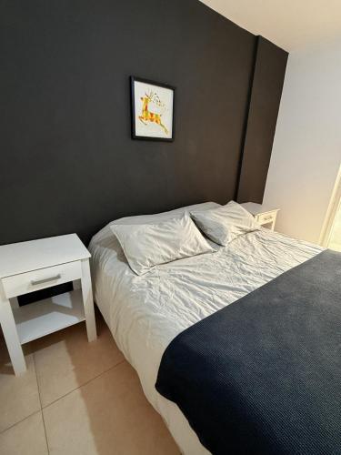 a bedroom with a bed and a white night stand at Moderno y funcional Dpto cerca del casco histórico de Salta in Salta